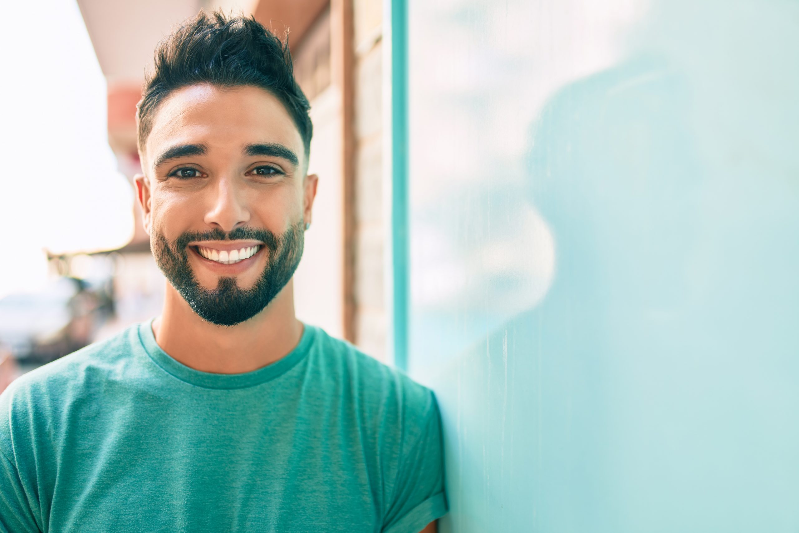 Young arab man smiling happy leaning on the wall at the city.