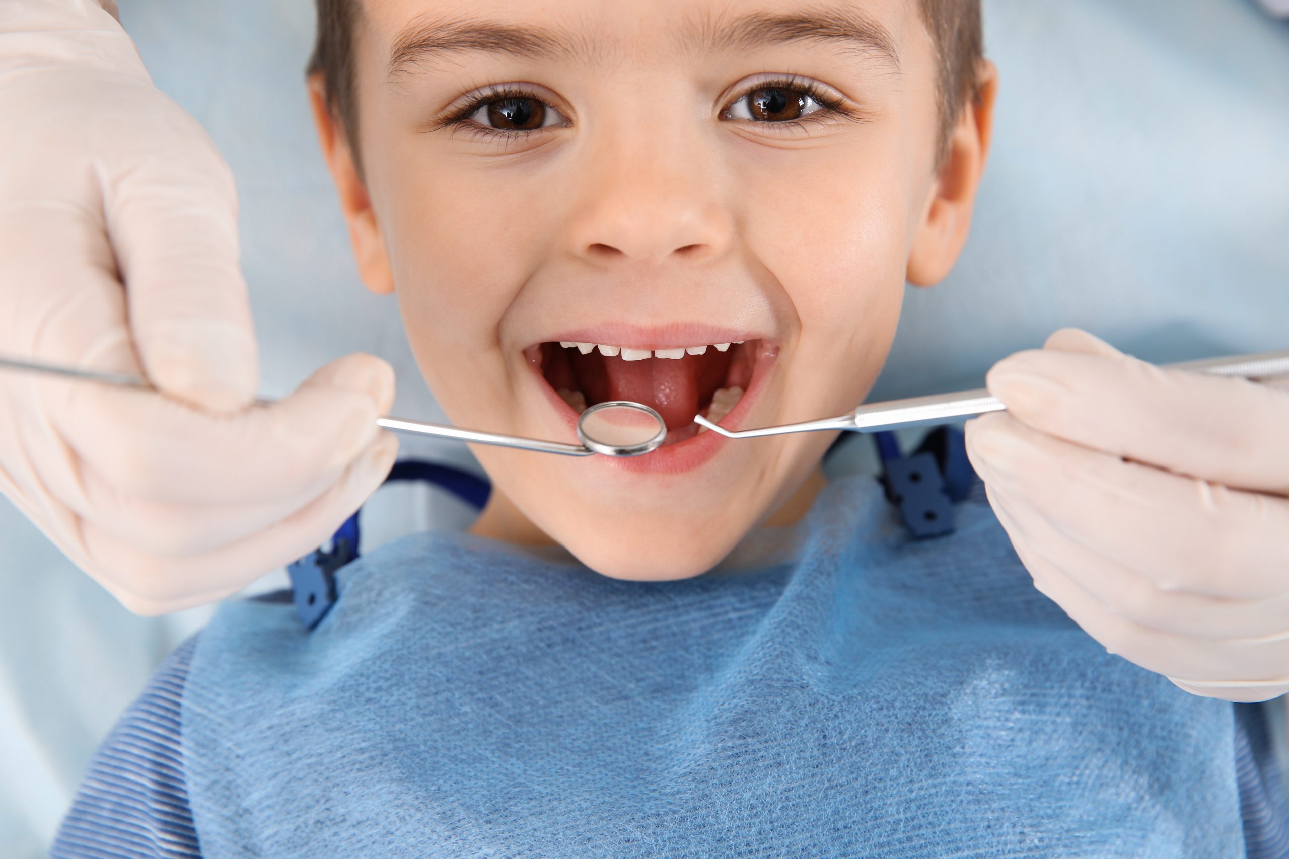 Dentist examining cute boy's teeth in modern clinic