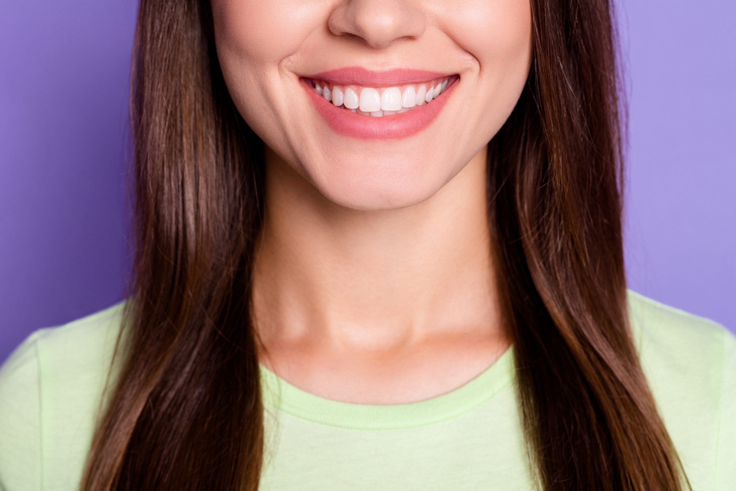 Closeup cropped photo of beautiful woman with brunette hair smiling with white teeth isolated on bright violet color background.