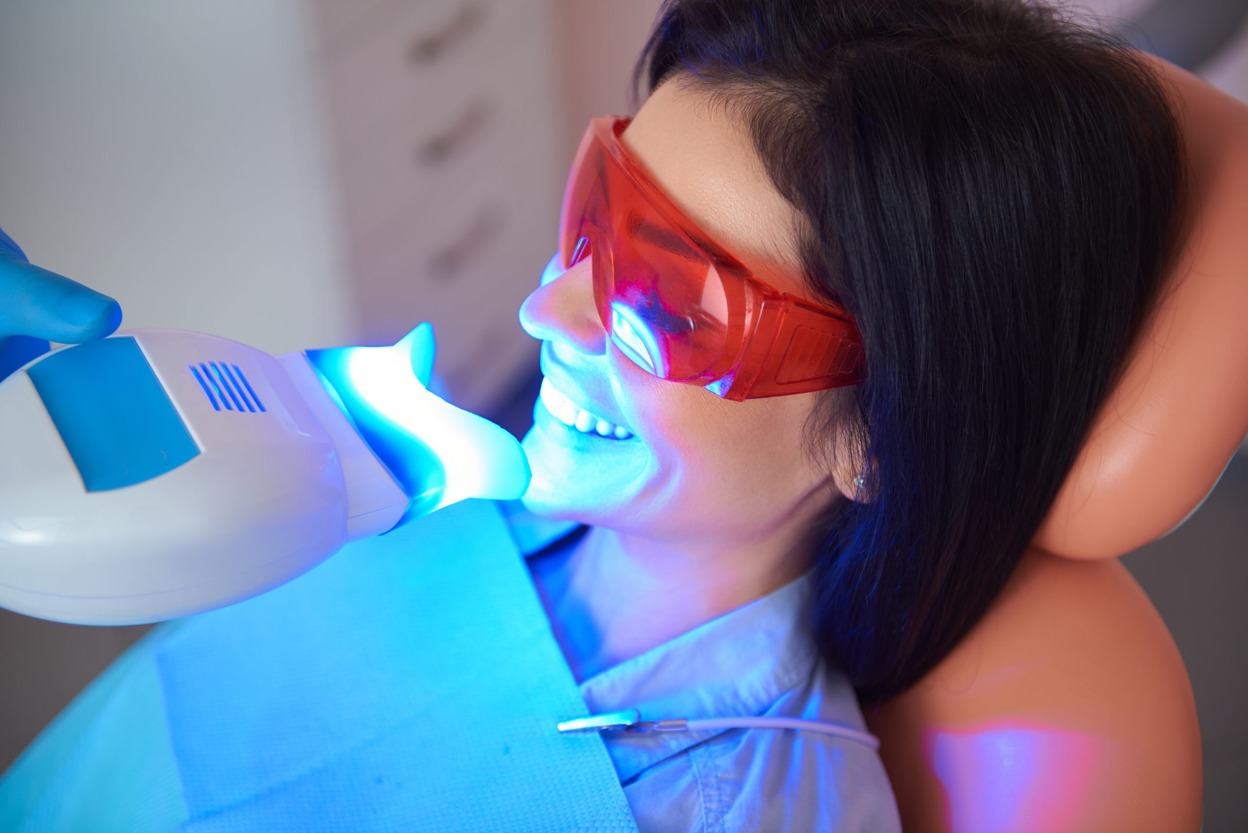 Pretty smiling lady in dental room doing teeth whitening