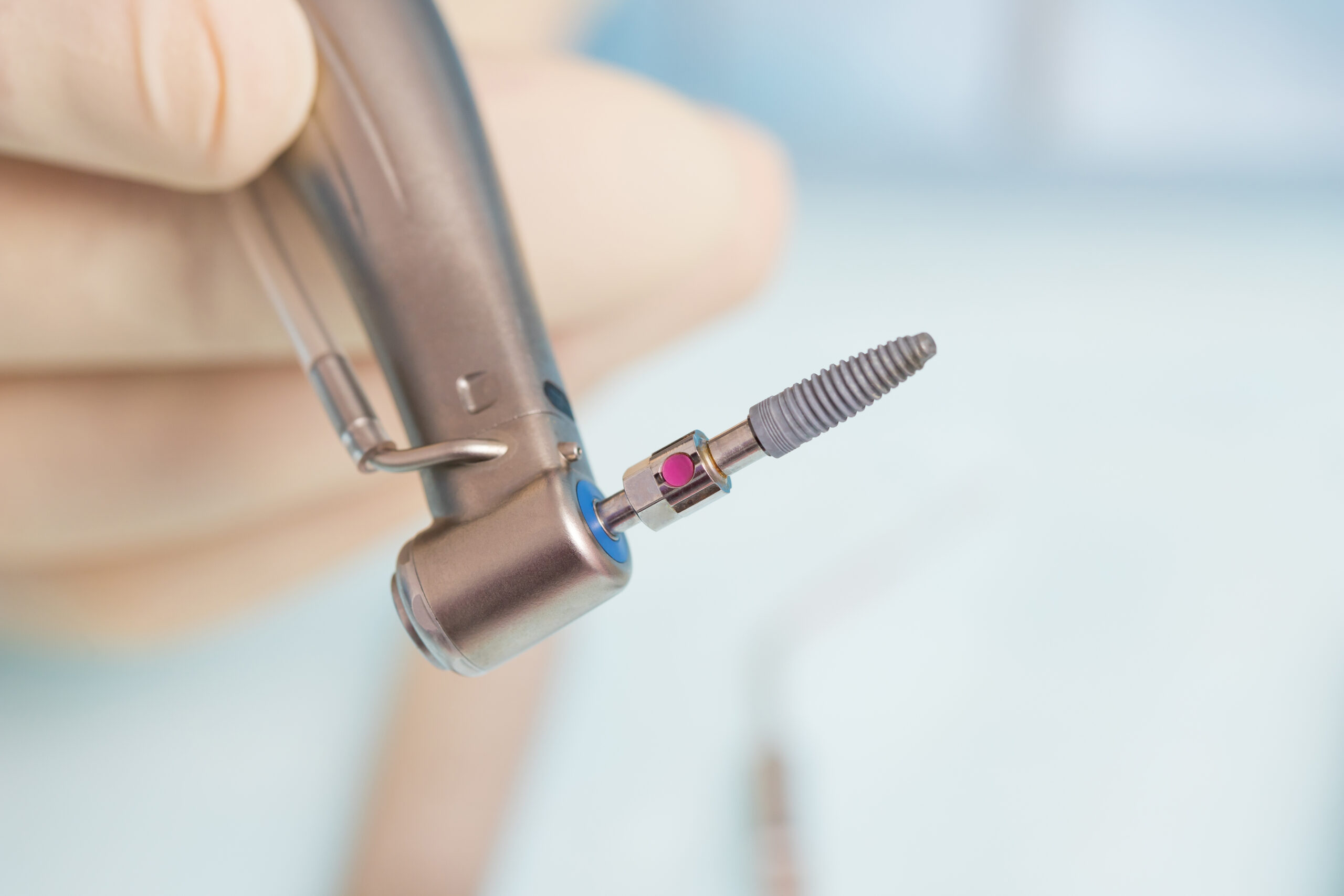 During the operation, the dentist holds implantation tools with a titanium implant. Close-up
