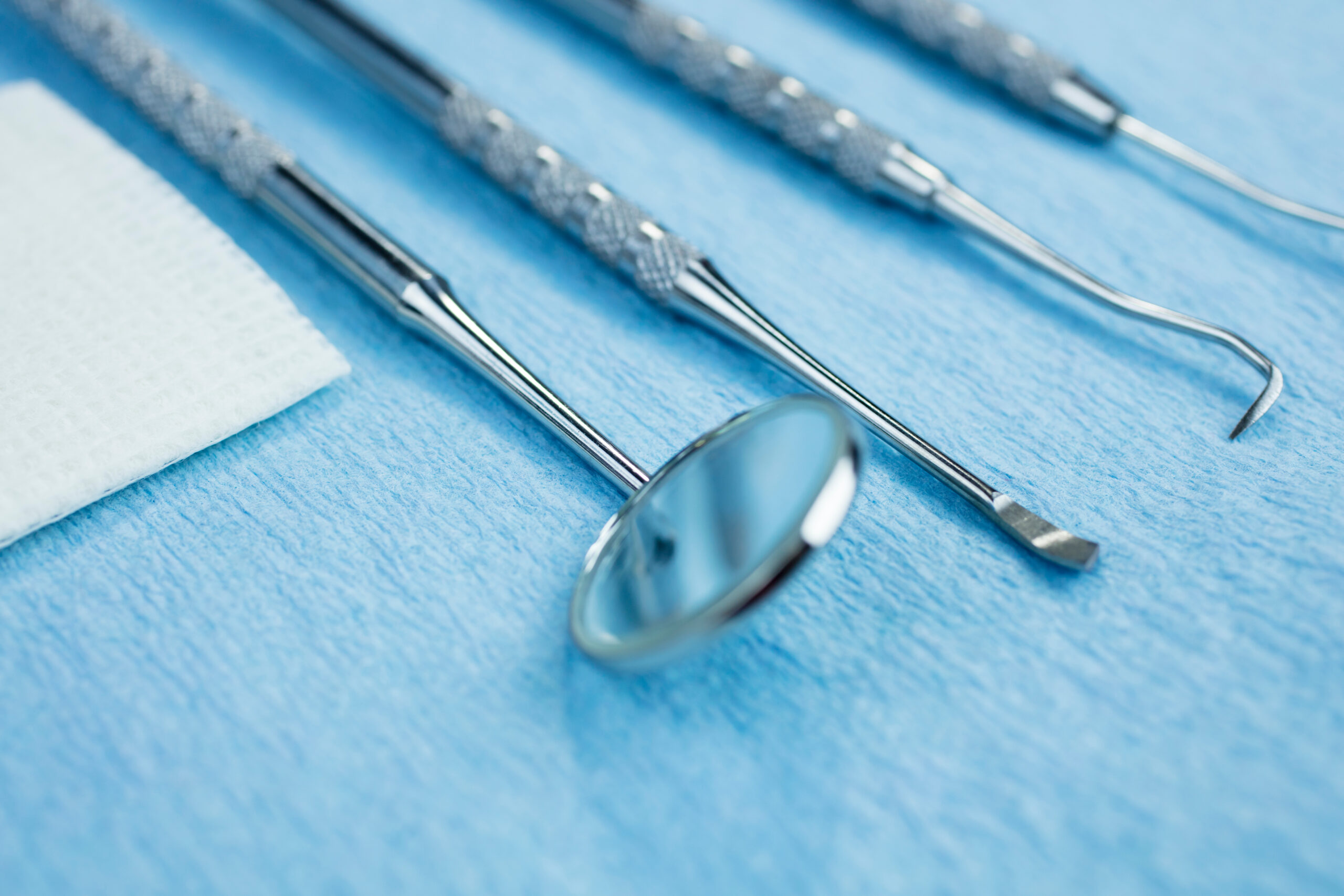 Dental Picks, Mirror and Gauze on a Paper Lined Tray